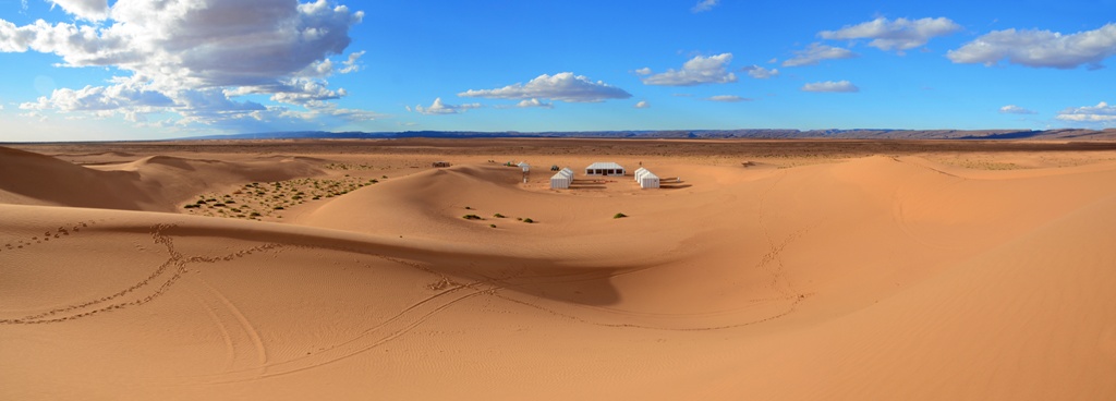 Landscape with golden dunes and tents in Erg Lihoudi desert, south of Morocco