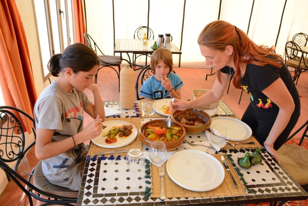 family enjoying tajine in Sahara, at Arawan
